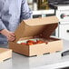 A person holding a Choice corrugated catering box of food.