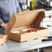 A woman holding a Choice cardboard catering box full of food.