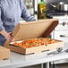 A person holding a Choice corrugated catering box full of food.