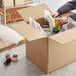 A person packing food in a Lavex heavy-duty corrugated cardboard box.