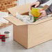 A person opening a Lavex cardboard box with cans of food inside.