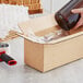 A hand pouring a brown bottle into a Lavex heavy-duty corrugated shipping box.