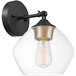 A Globe matte black and gold wall sconce with clear glass shade over an Edison bulb.