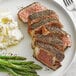 A plate of food with meat, mashed potatoes, and asparagus with a spoon and fork on the side.