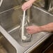 A hand using a Franmara wine decanter brush to clean a glass pitcher.