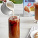 A person pouring Silk almond milk into a glass of iced tea.