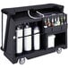 A black Cambro portable bar cart with bottles on a metal surface.