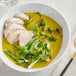 A bowl of curry soup with chicken and vegetables.