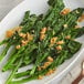 A plate of greens with brown crumbs on top with McCormick Culinary Minced Garlic on a table.