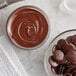 A bowl of chocolate spread with chocolate chips and chocolate buttons.