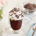 A glass cup of coffee with whipped cream and Republica del Cacao Vinces Cacao Nibs.