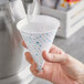 A hand pouring water into a Choice paper cone cup.