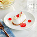 A white dessert on a plate with red jelly.