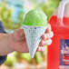 A hand holding a Choice paper cone filled with green ice cream.
