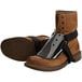 A close up of a pair of brown boots with black METGUARD straps attached to them.