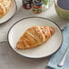 A plate with a croissant and a plate with croissants on a table with a cup of coffee.