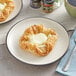 A plate with a Gourmand cream cheese danish and butter on it.