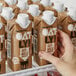 A person's hand reaching for a brown carton of Oatly Chocolate Oat Milk.