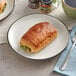 A plate with two spinach ricotta pastries on it on a table.