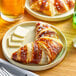 A plate with a Gourmand butter croissant on it.