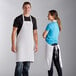 A man and woman wearing white Choice Poly-Cotton aprons.