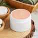 A white container of pink face cream.