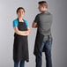 A man and woman wearing Choice black bib aprons.