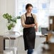 A woman wearing a black Choice Customization bib apron.