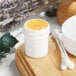 A white polypropylene jar filled with yellow substance on a wooden surface.