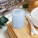 A Clear Regular Wall Polystyrene jar of blue scrub on a wooden surface.