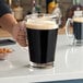 A person pouring beer into a Libbey glass pitcher.