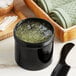 A black container of green gel on a white surface.
