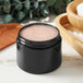 A black container with a round lid holding hair gel.