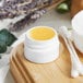 A white Thick Wall Polypropylene jar filled with yellow liquid on a wooden surface.