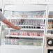 An Avantco white vertical air curtain merchandiser with a man standing in front of it.