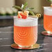 A Zelda double old fashioned glass with an orange cocktail and garnish.