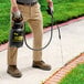 A man using a black Chapin Poly Foamer / Sprayer to spray a sidewalk.