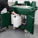 A person pushing a green Cambro CamKiosk portable sink cart with a faucet.