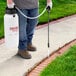 A man using a Chapin Pro Series multi-purpose sprayer to spray a lawn.