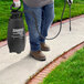 A man using a Chapin 3 gallon black and white sprayer on a lawn.