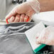 A person in a plastic glove washing a Vigor paella pan with a sponge.