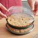 A person holding a Solut clear plastic lid on a container with food in it.