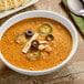 A bowl of Chef Francisco Baja Chicken Enchilada Soup with crackers and a spoon.