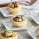 Unbaked La Rose Noire round pastry shells on small square plates.
