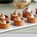 A plate of La Rose Noire mini round graham cracker tart shells filled with desserts.