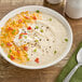 A bowl of TrueSoups Loaded Baked Potato Soup with cheese and green onions.