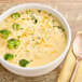 A bowl of Chef Francisco Broccoli Cheese Soup with florets and a spoon.