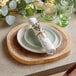 An Acopa round acacia wood serving board with a napkin on a table.