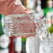 A person pouring whiskey from an Acopa cut glass decanter into a glass.