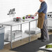 A man cutting vegetables on a Regency stainless steel work table in a professional kitchen.